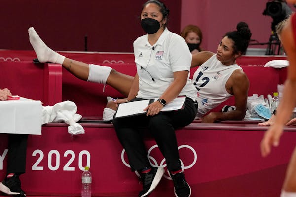 United States’ Jordan Thompson, rear, lies injured on the bench during the women’s volleyball preliminary round match against the Russian Olympic 