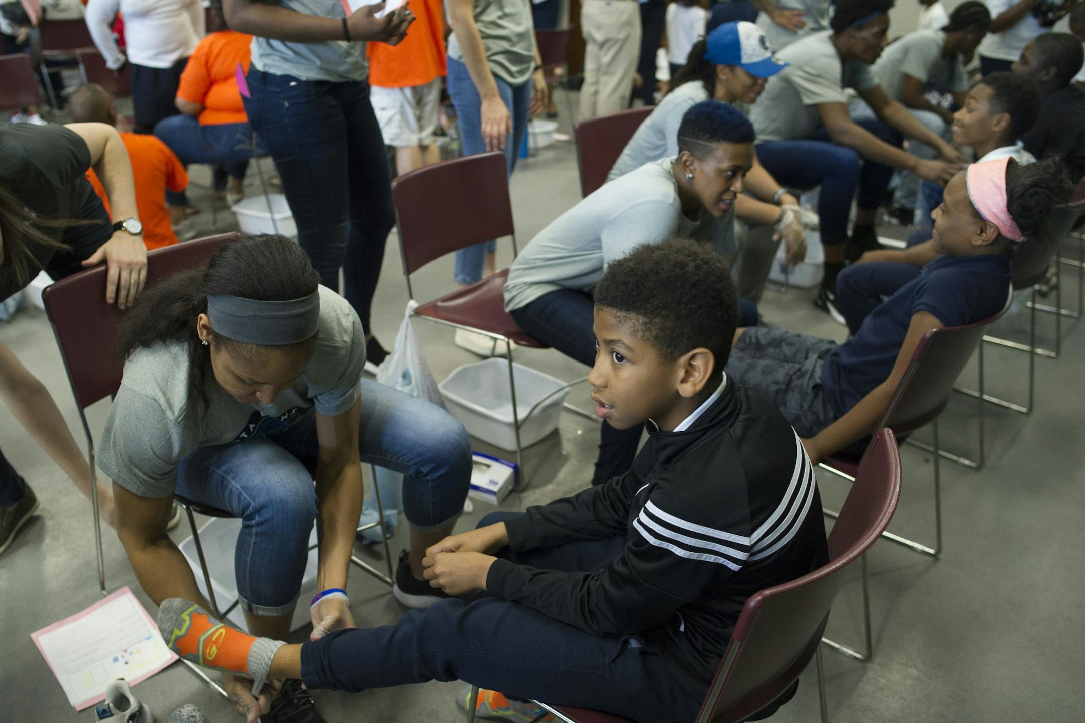 WNBA Champion Minnesota Lynx Forward Maya Moore removes a student's socks before washing his feet at Payne Elementary School in Washington, Wednesday, June 6, 2018. Payne Elementary has the highest homeless student population in the district.