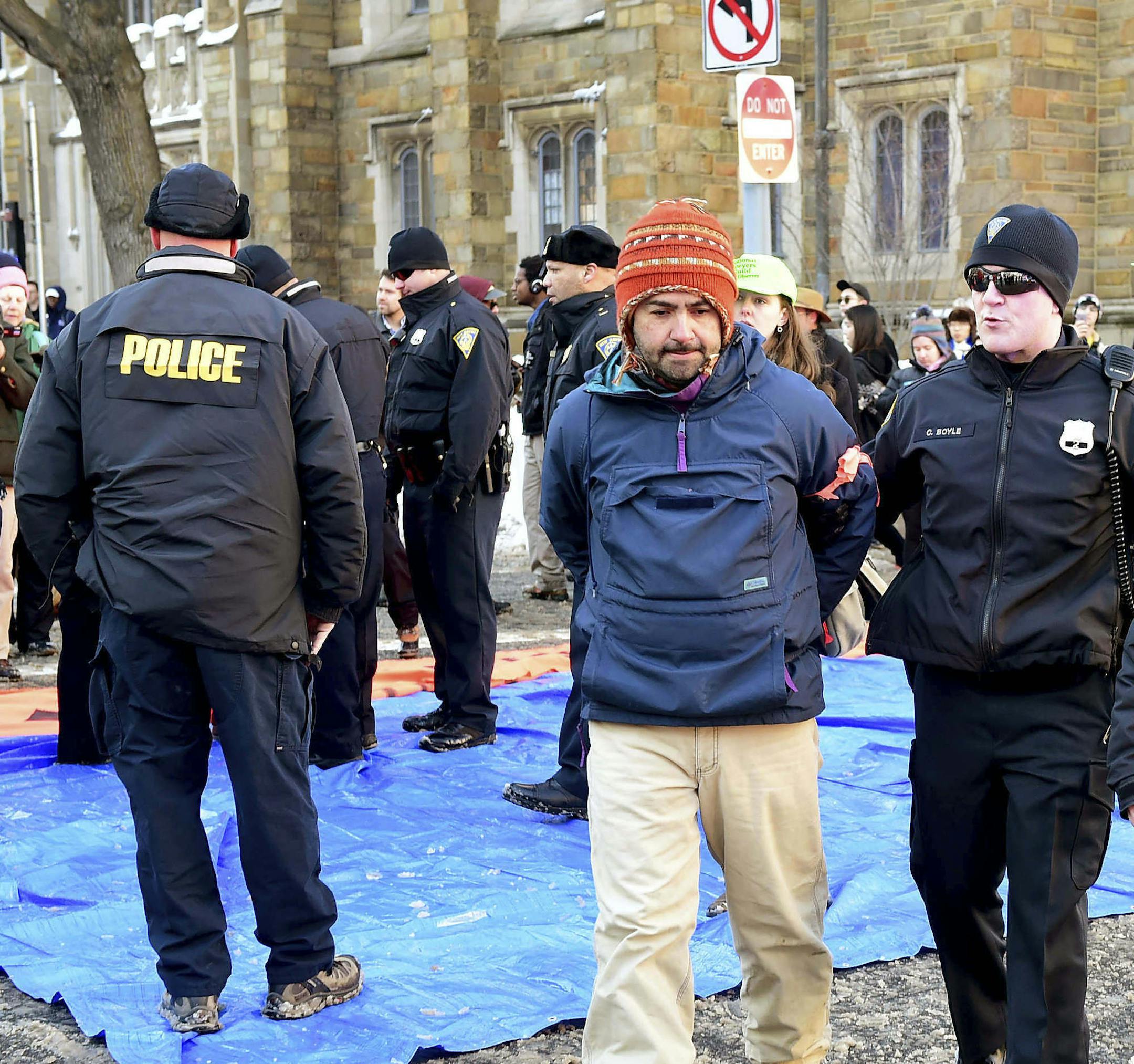 John Lugo, center, of Unidad Latina en Accion of New Haven, is arrested during a demonstration after some protesters blocked the intersection of Elm and College Streets in New Haven, Conn., Friday, Feb. 10, 2017, and refused to move. The protesters are in favor of changing the name of Yale University's Calhoun College. The peaceful arrests were pre-planned and coordinated between the demonstrators and New Haven Police. (Peter Hvizdak/New Haven Register via AP)