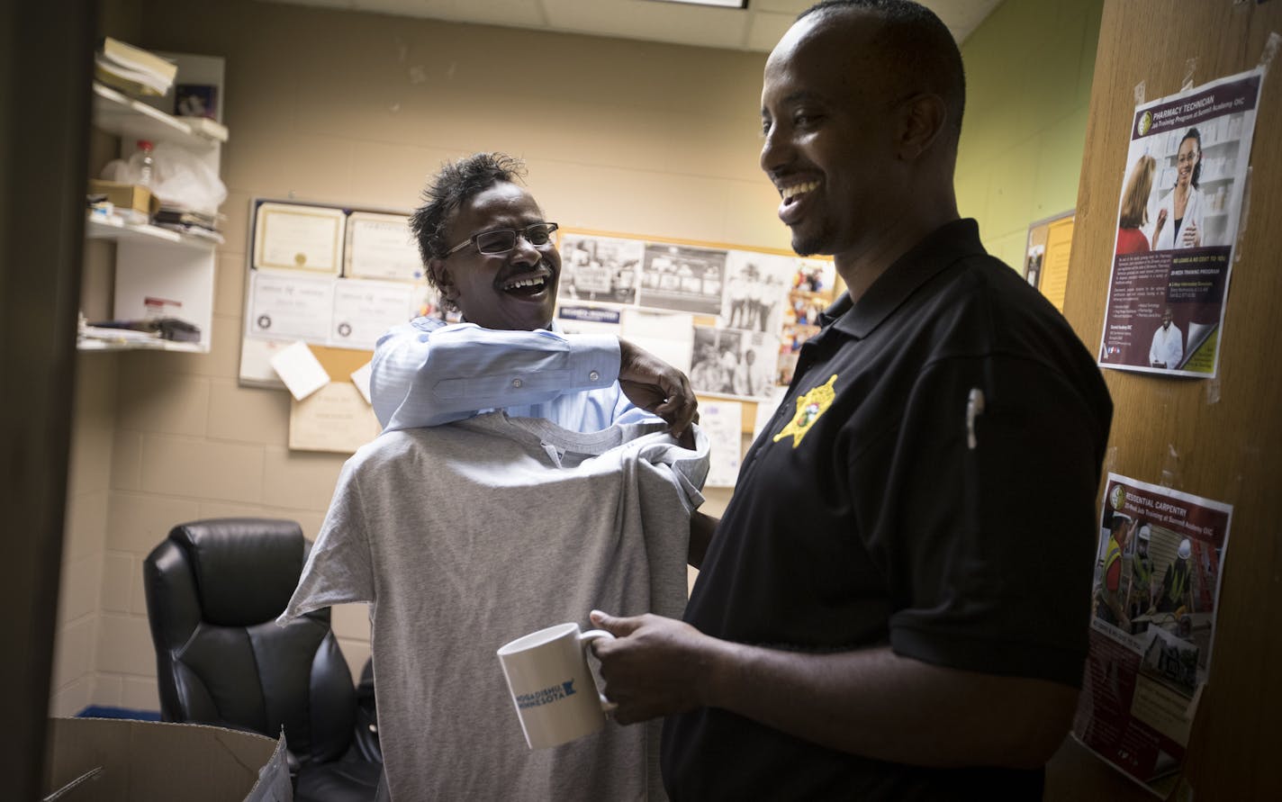 Abdirizak Bihi, left, social activist and community organizer, handed Abdi Mohamed, community liaison for the Hennepin County Sheriff&#x2019;s office, a mug and T-shirt as he stopped by the Brian Coyle Center on Tuesday July 19, 2016, in Minneapolis, Minn. ] RENEE JONES SCHNEIDER &#x2022; renee.jones@startribune.com