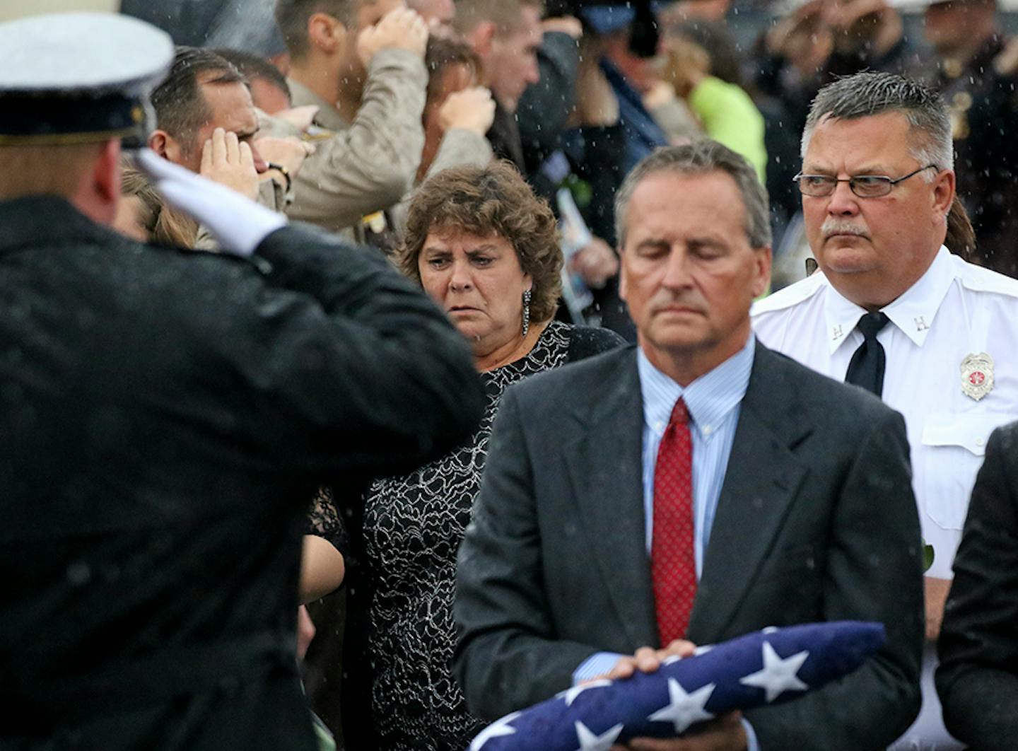 Thousands of law enforcement officers poured into Aitken on a drizzly morning to bury one of their own, Deputy Steven M. Sandberg. Here, Sandberg's wife Kristi (center) walks out of the school after the funeral. ] Brian.Peterson@startribune.com Aitkin, MN - 10/23/2015