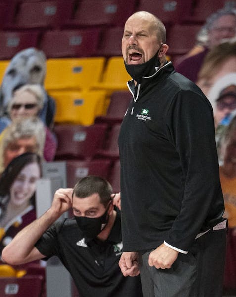 North Dakota Fighting Hawks head coach Paul Sather pulled down his mask to yell instructions out to his team during the first half of their game again