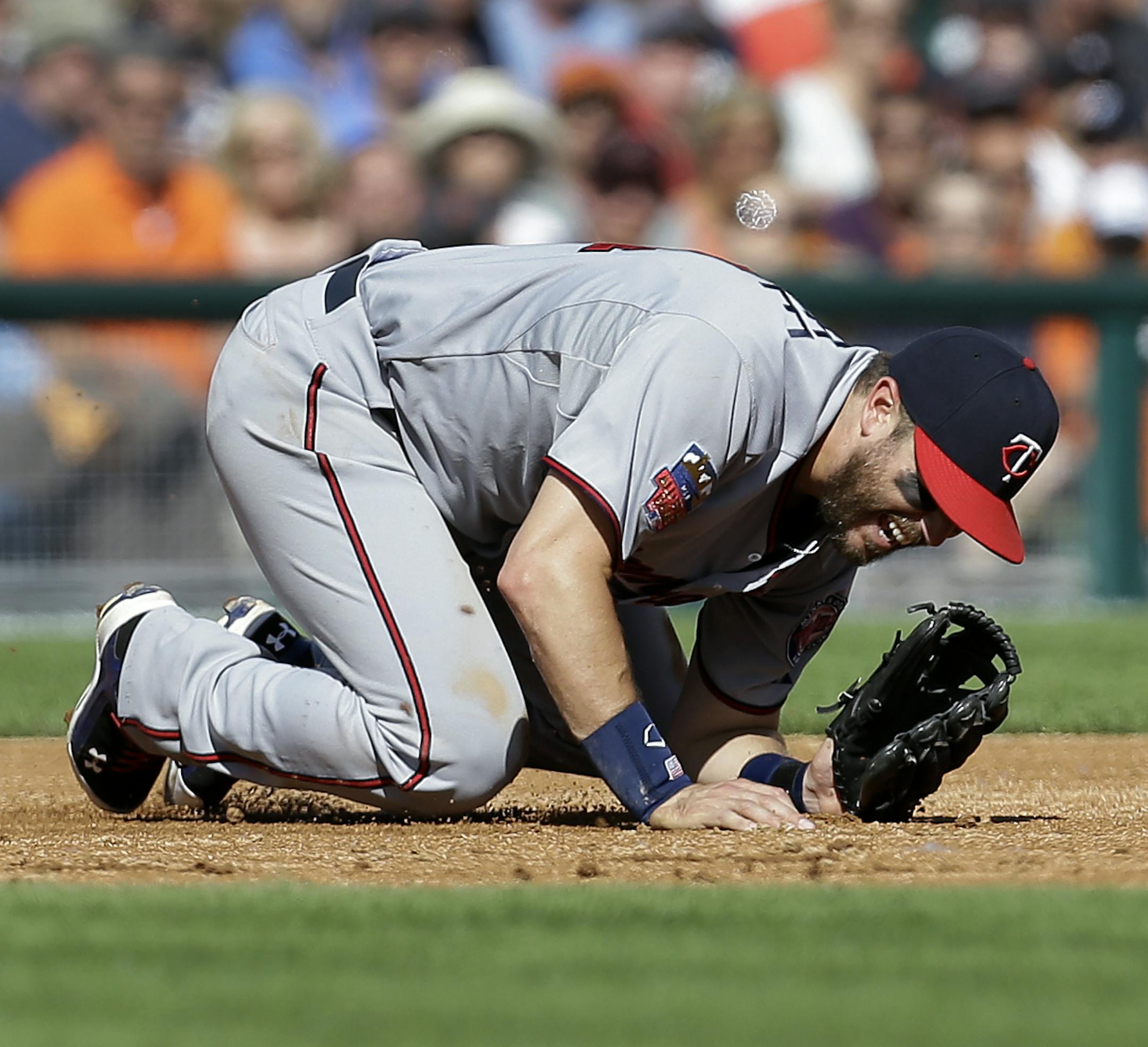 Minnesota Twins third baseman Trevor Plouffe grimaces after deflecting a Detroit Tigers' J.D. Martinez line drive in the third inning of a baseball game in Detroit, Saturday, June 14, 2014. (AP Photo/Paul Sancya)