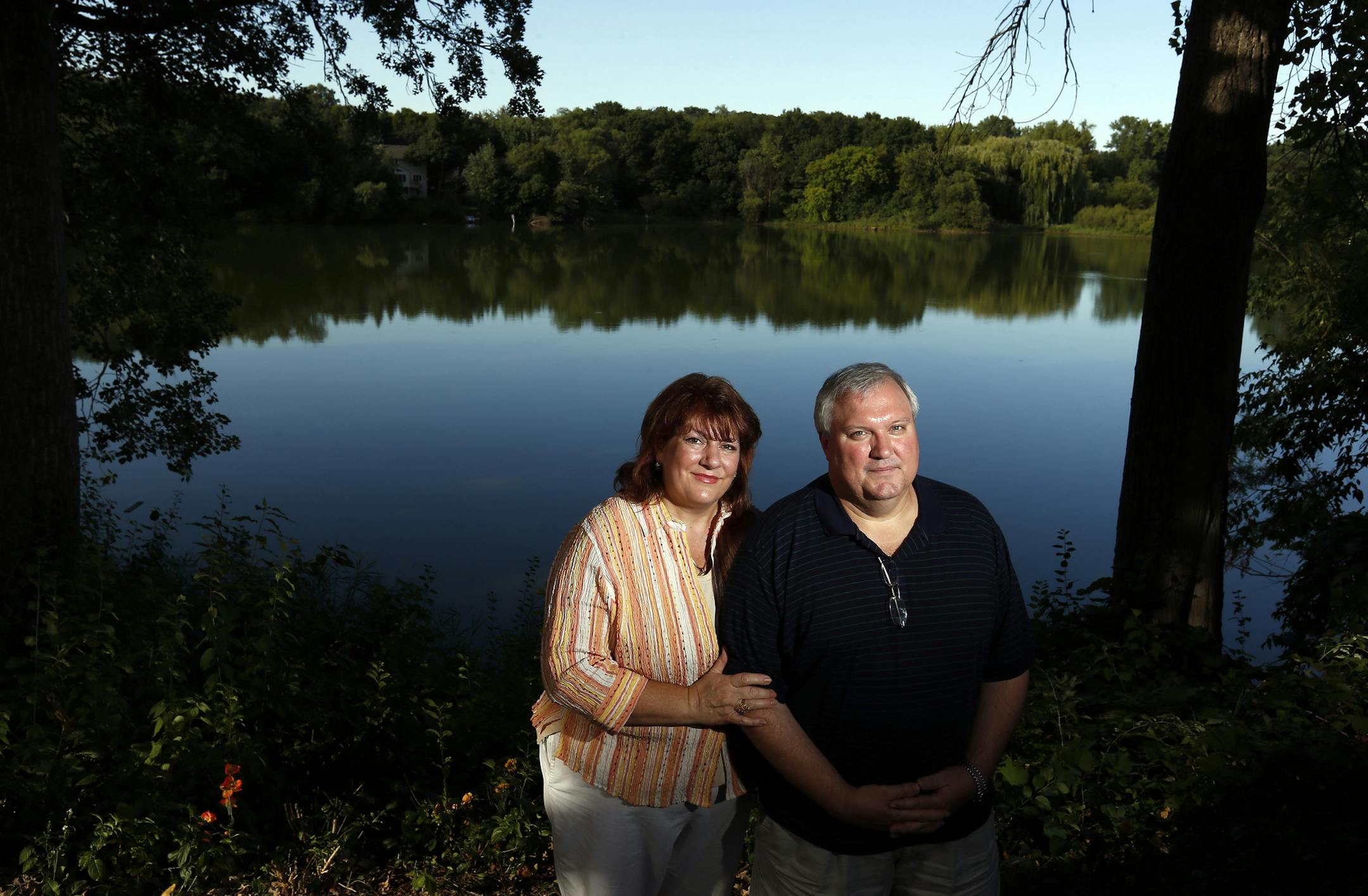 Kate and Paul Habegger photographed near the lake that adjoins their backyards in Apple Valley. (The Habegger's own two homes that are side by side, this is the backyard of one of their parents' home) ] CARLOS GONZALEZ cgonzalez@startribune.com September 3, 2013, Apple Valley, Minn., A fourth south metro lake will be drained in attempt to revive its water quality. Starting later this month, the water in Apple Valley 37-acre Long Lake will drain under Pilot Knob Road into adjoining Farquar Lake i