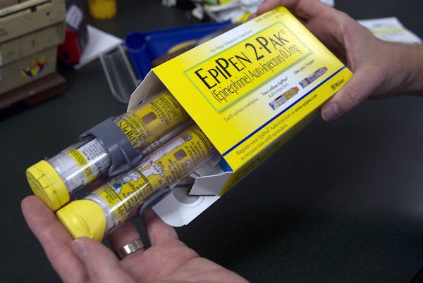 FILE - In this July 8, 2016, file photo, a pharmacist holds a package of EpiPens epinephrine auto-injector, a Mylan product, in Sacramento, Calif. Myl