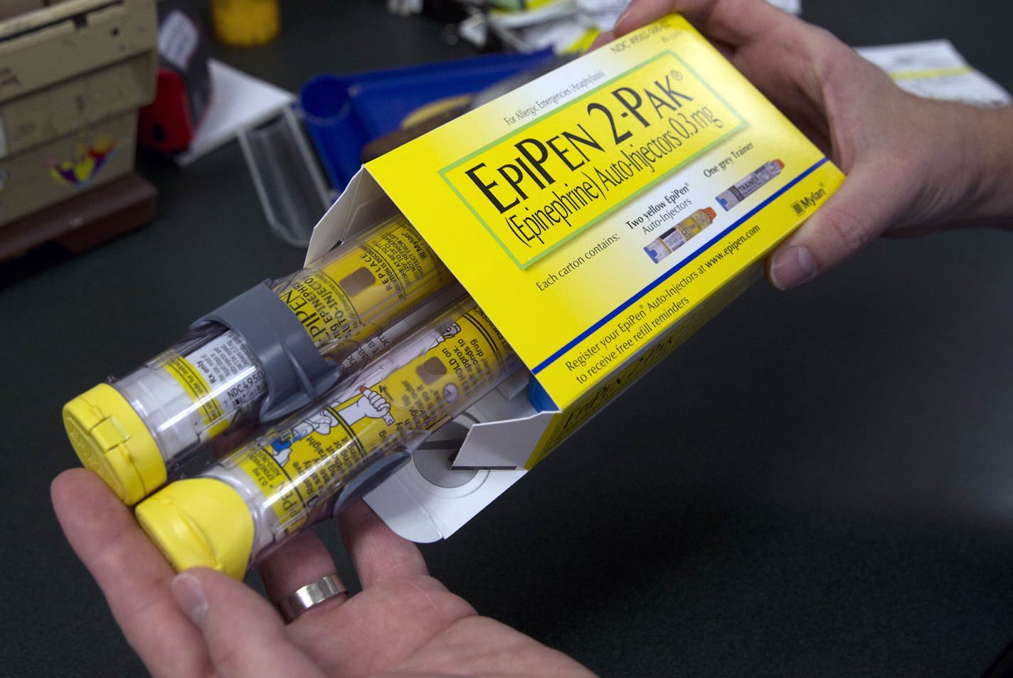 FILE - In this July 8, 2016, file photo, a pharmacist holds a package of EpiPens epinephrine auto-injector, a Mylan product, in Sacramento, Calif. Mylan said it will make available a generic version of its EpiPen, as criticism mounts over the price of its injectable medicine. (AP Photo/Rich Pedroncelli, File)