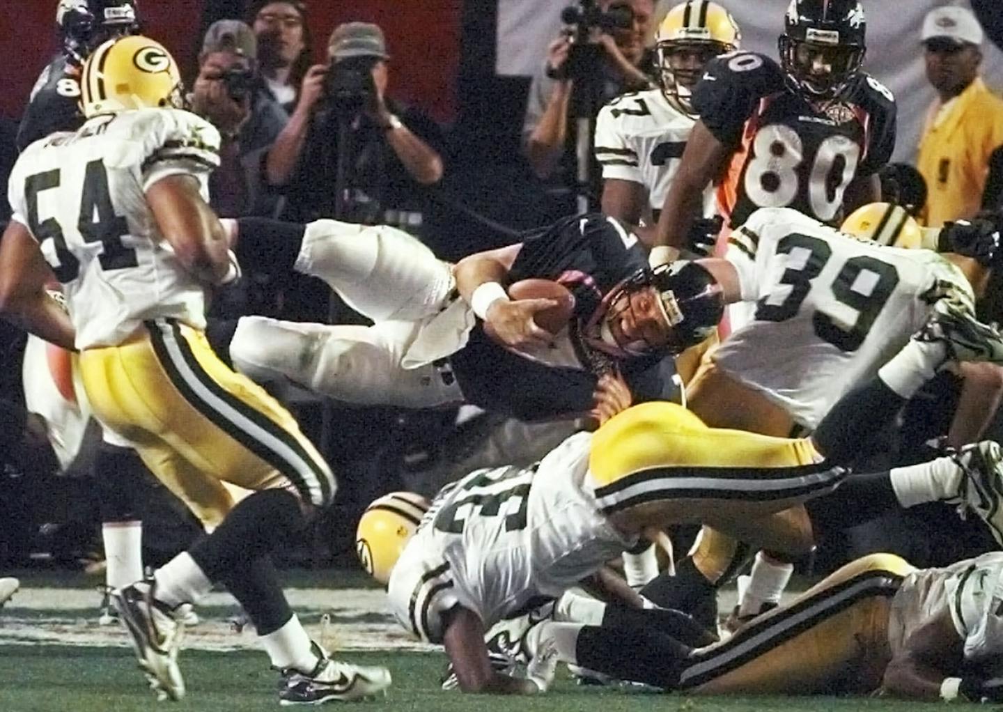 FILE - In this Jan. 25, 1998, file photo, Denver Broncos quarterback John Elway is upended Green Bay Packers' Brian Williams (51) and Elroy Butler (36) while running for a first down during the third quarter of NFL football's Super Bowl XXXII in San Diego. The play extended a drive that resulted in a touchdown that broke a tie. (AP Photo/Elise Amendola, File) ORG XMIT: NY151