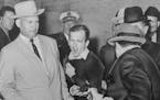 Lee Harvey Oswald, accused assassin of President John F. Kennedy, reacts as Dallas night club owner Jack Ruby, foreground, shoots at him from point bl