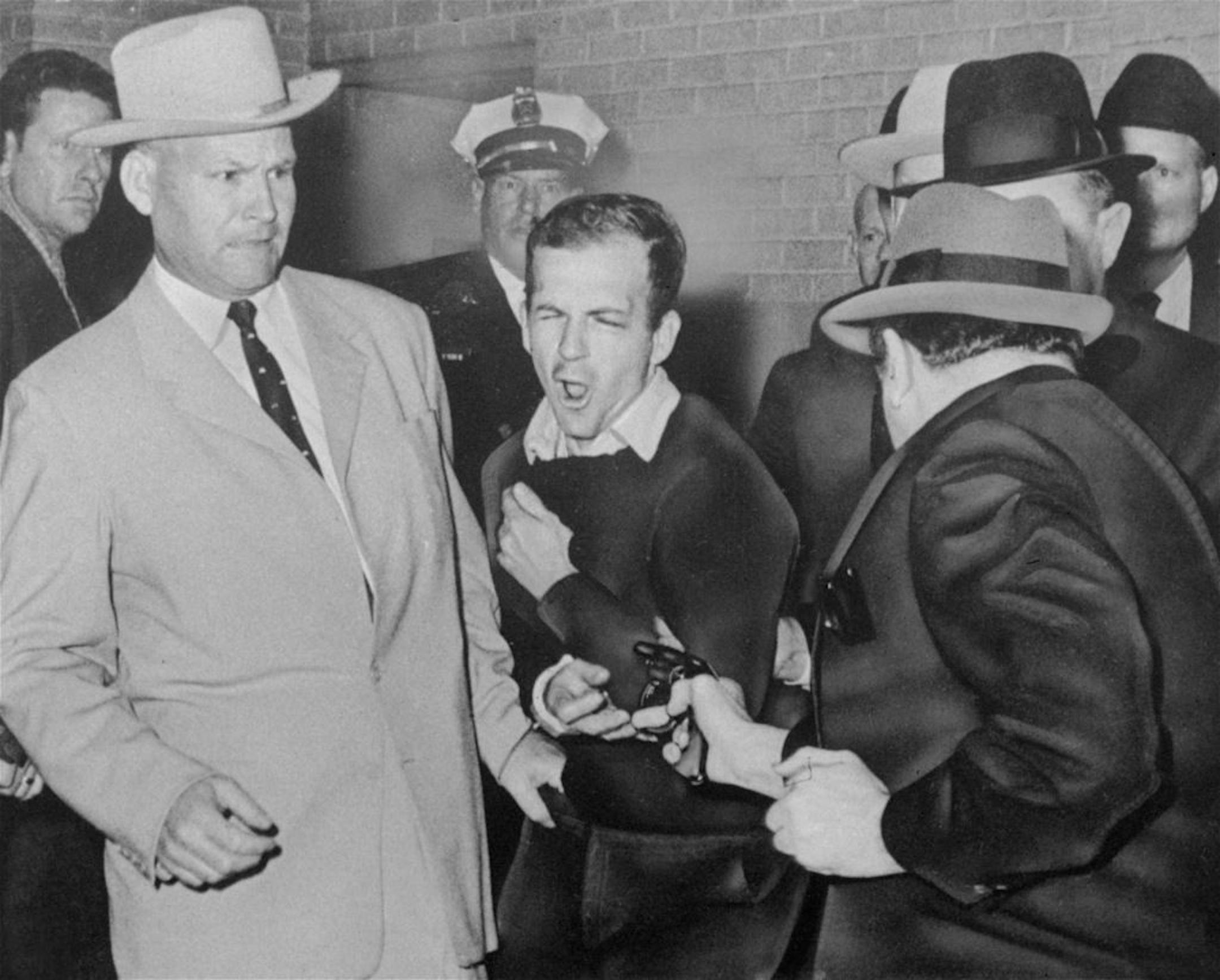 Lee Harvey Oswald, accused assassin of President John F. Kennedy, reacts as Dallas night club owner Jack Ruby, foreground, shoots at him from point blank range in a corridor of Dallas police headquarters, in this Nov. 24, 1963 file photo. Plainclothesman at left is Jim A. Leavelle.