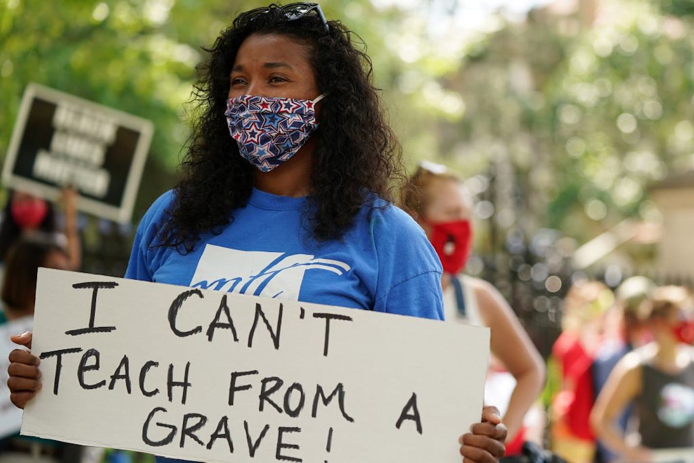 Lindsey West who teaches 5th grade at Clara Barton Open School held a sign as she and others protested in person learning this fall outside in Governor's Residence in late July.