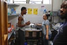 David Williams, 22, left, chats with Ashley Bosco, a youth worker, as Rayfield Drake, 24, looks on in the kitchen area at The Crib, a place for homele