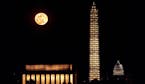 The moon rises behind the Washington Monument as the scaffolding around it is illuminated after a lighting ceremony to celebrate the re-opening of the