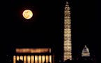 The moon rises behind the Washington Monument as the scaffolding around it is illuminated after a lighting ceremony to celebrate the re-opening of the