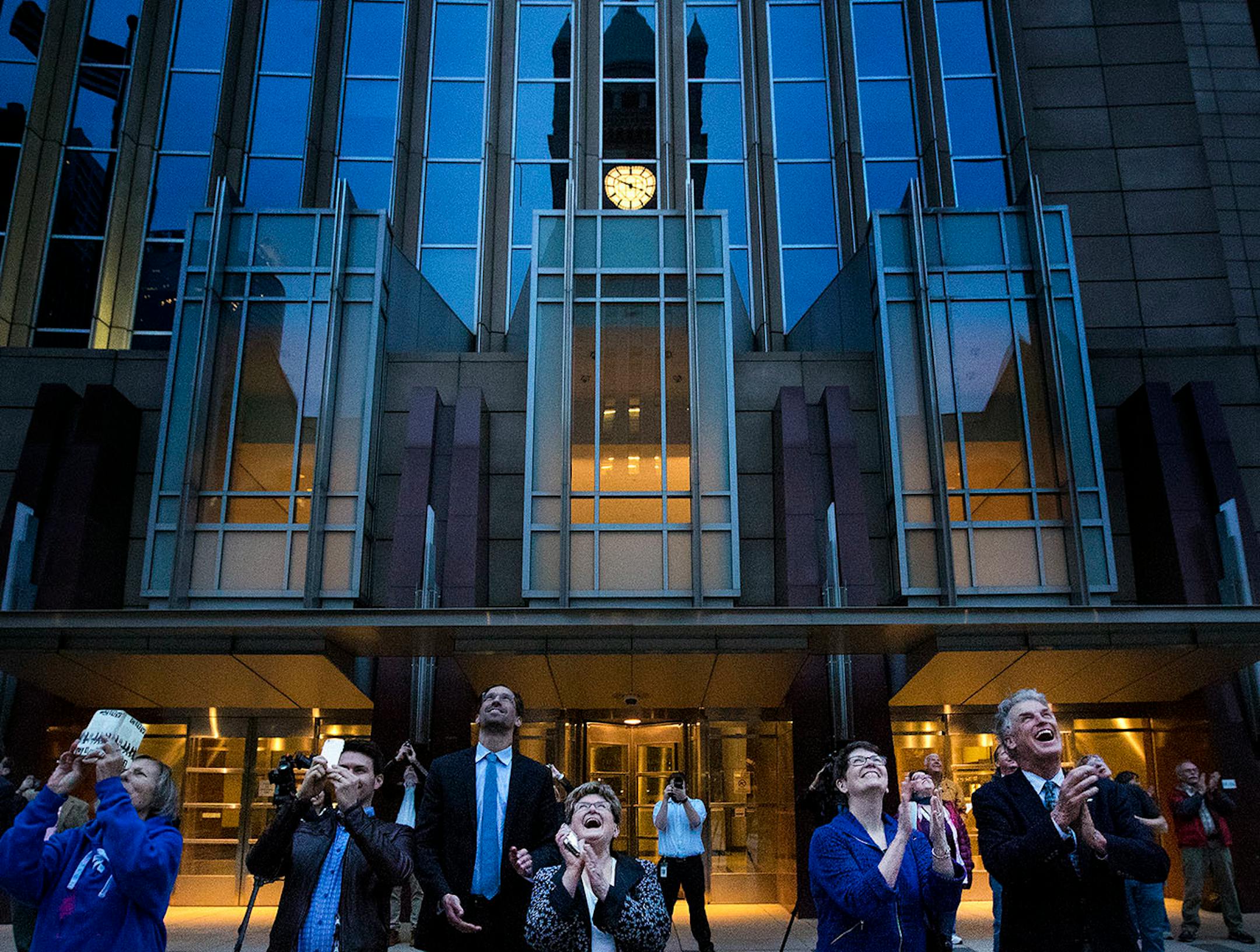 Minneapolis City Council President Barb Johnson (right) Hennepin County Commissioner Jan Callison (second from right) and Commissioner Peter McLaughlin (right) applauded after the lighting of the clock at Minneapolis City Hall.