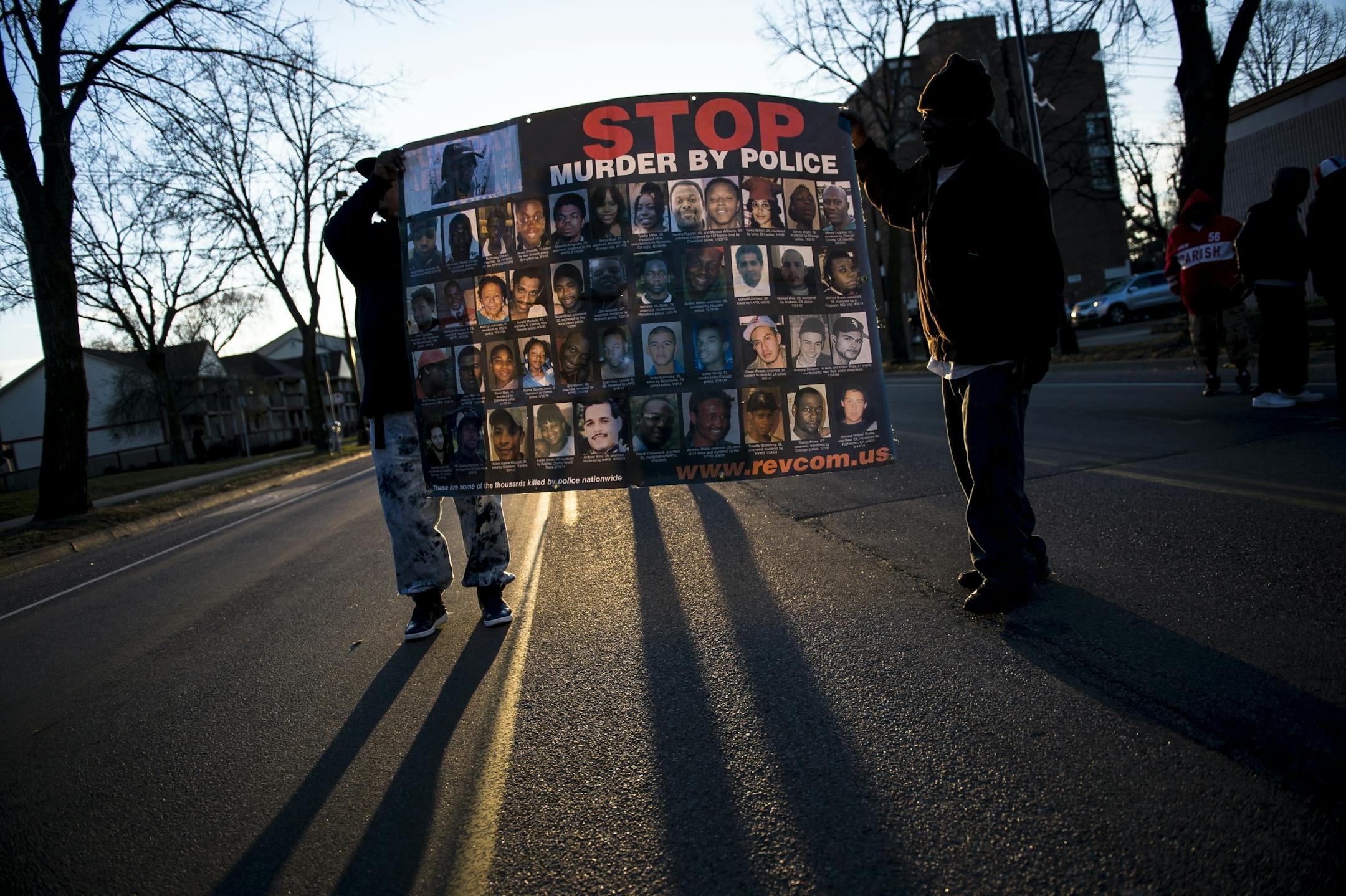 Demonstrators held a sign with the faces and names of men, women and children killed by police during a vigil at the Jamar Clark memorial Friday.