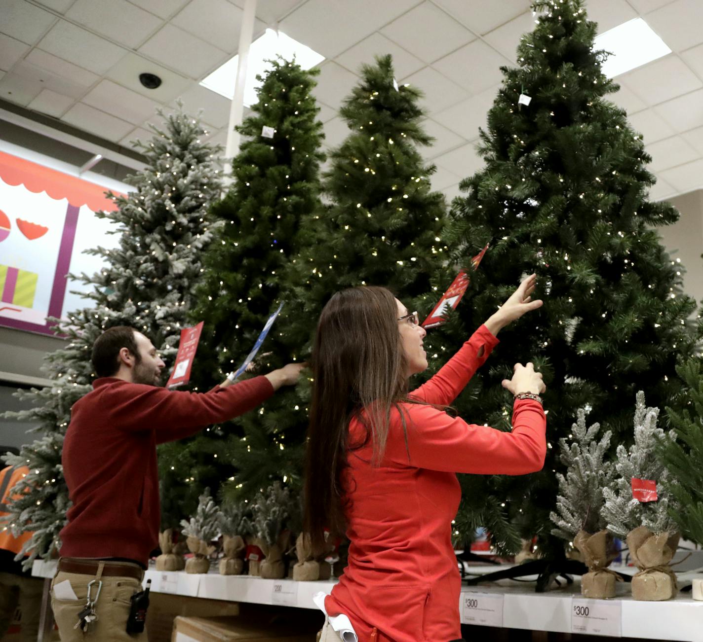 In this Friday, Nov. 16, 2018, photo, employees work on the presentation of Christmas trees at a Target store in Bridgewater, N.J. Shoppers are spending freely heading into the holidays, but heavy investments and incentives like free shipping by retailers are giving Wall Street pause. Target Inc., Kohl's Corp., Best Buy Co. and TJX Cos. all reported strong sales at stores opened at least a year. (AP Photo/Julio Cortez)