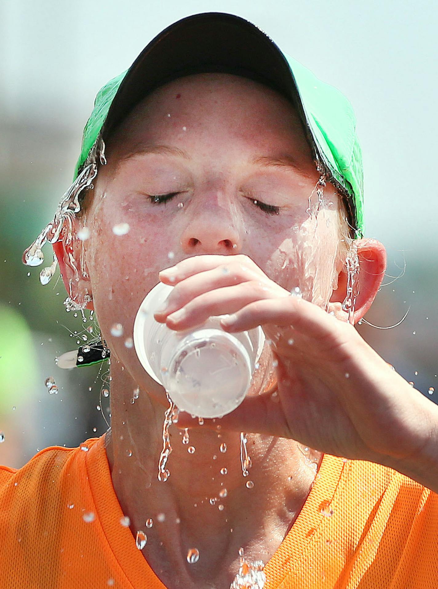 t6.18.16 Bob King -- kingRACE0619c35 -- Trying to keep cool after getting to the top of Lemon Drop Hill, Melissa Flucke of Green Bay half-splashes and half-drinks a cup of cold water she grabbed from a volunteer in Grandmas Marathon. Bob King / rking@duluthnews.com