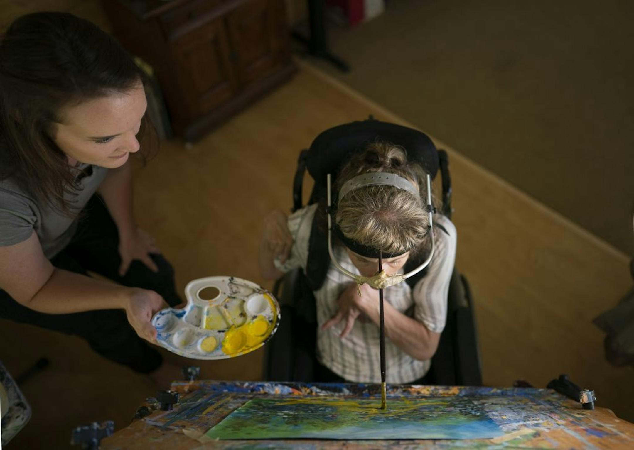 Kari Wagner worked on a painting while Carrie Ingish, a therapeutic recreation specialist with Gillette Children's Specialty Healthcare, held the palate for her.