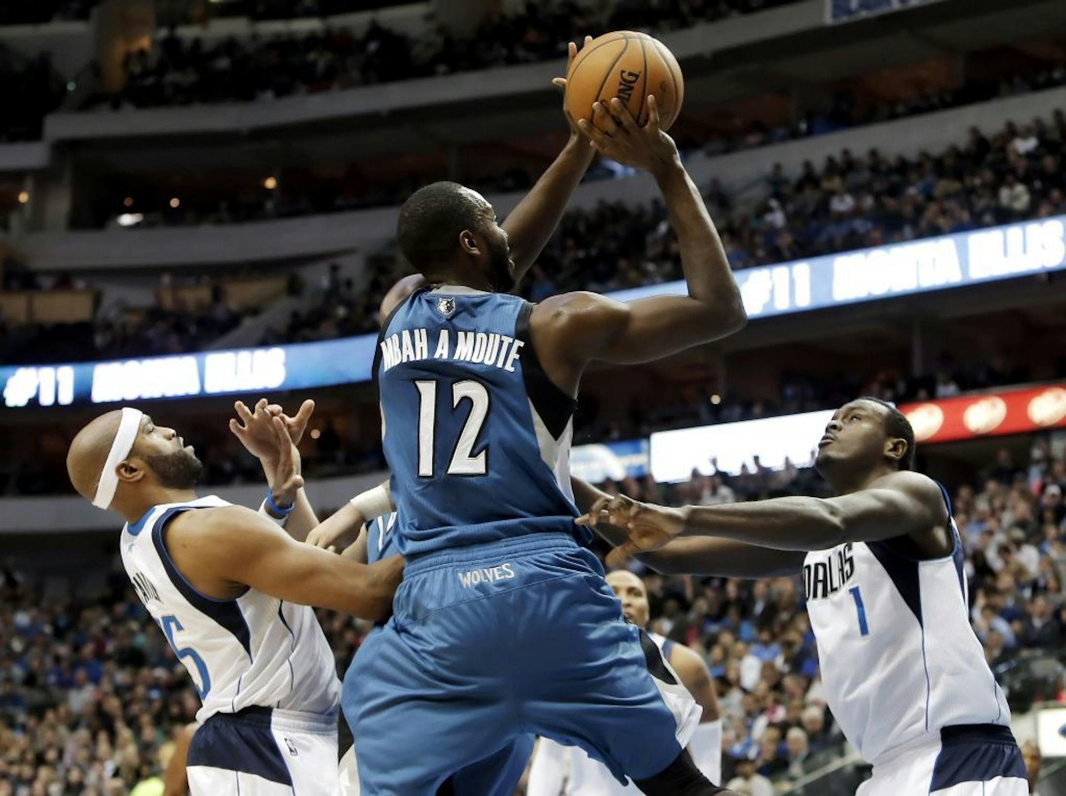 Minnesota Timberwolves forward Luc Richard Mbah a Moute (12) attempts a shot as Dallas Mavericks Vince Carter (25) and Samuel Dalembert (1) defend during the first half of an NBA basketball game Saturday, Nov. 30, 2013, in Dallas.