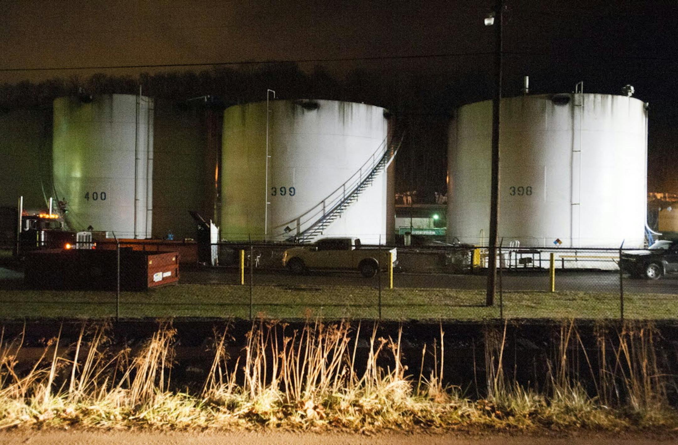 Chemical tanks are illuminated from the lights of emergency crews during clean up at the West Virginia American Water Plant on the Elk River in Charleston, W. Va.