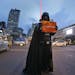 An activist in a Darth Vader costume holds a poster during a rally condemning Thursday's attack, outside the Starbucks cafe where it took place in Jak