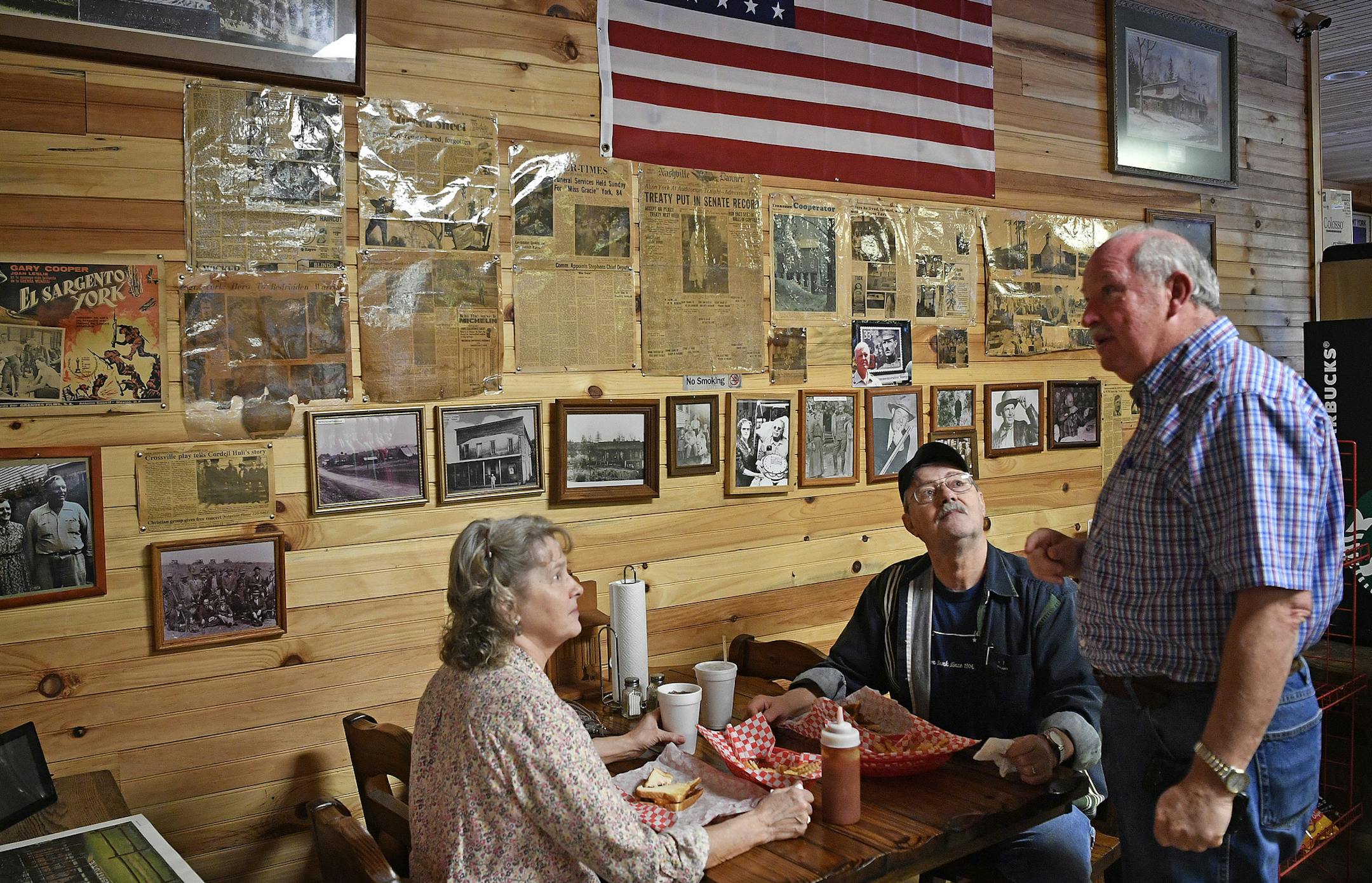 In this Feb. 21, 2018 photo, local residents Janet and Bruce Patton talk with retired Col. Gerald York in a market York owns in Pall Mall, Tenn., where the wall holds articles that recount the exploits of his famous grandfather Alvin C. York, a renowned hero of World War I. His granddad earned the Medal of Honor for heroism in October 1918 near Chatel-Chehery, France. (Larry McCormack/The Tennessean via AP)