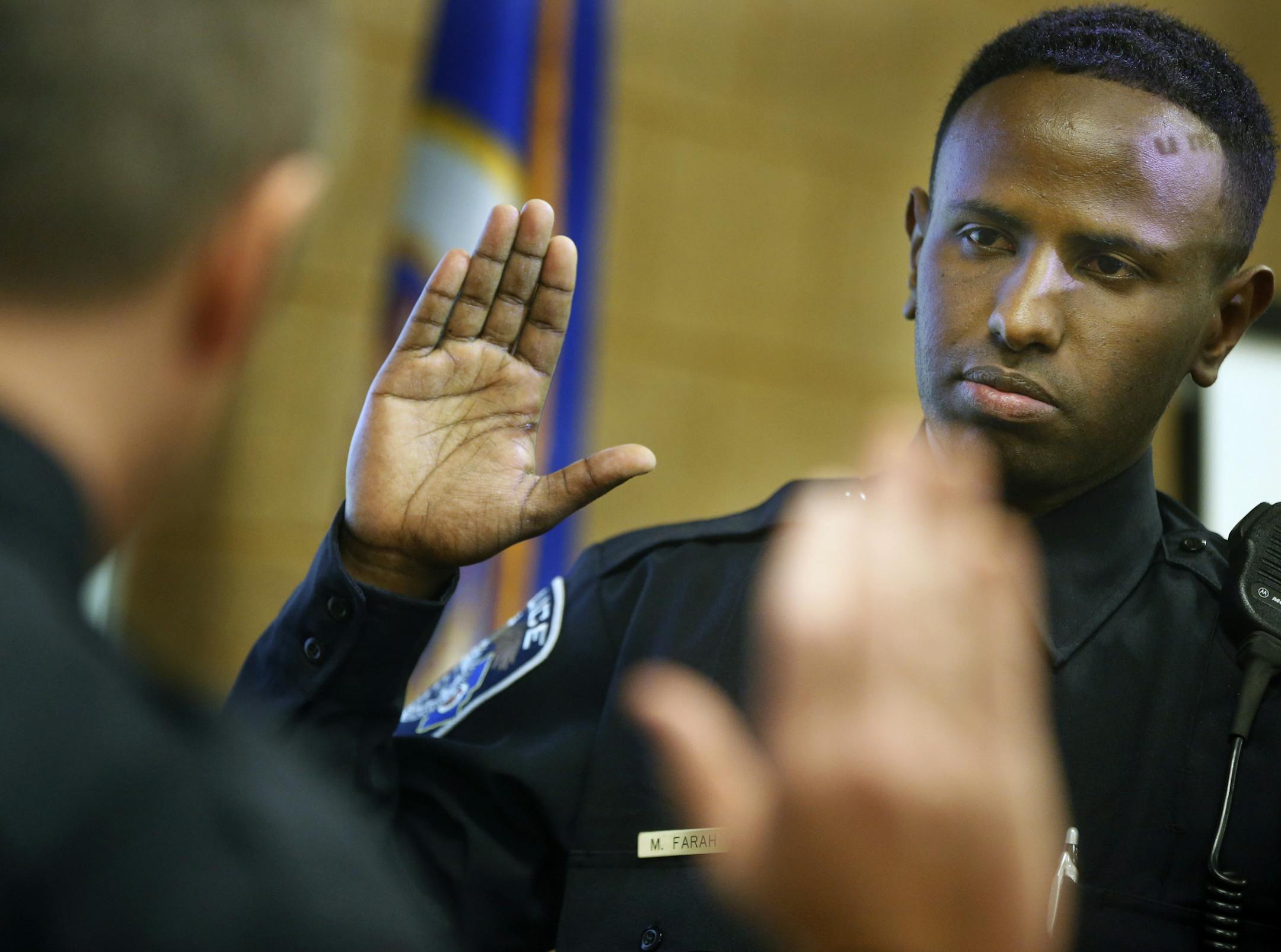 Columbia Heights police chief Scott Nadeau swears in its first Somali officer Mohammed Farah.] Richard Tsong-Taatatarii@startribune.com