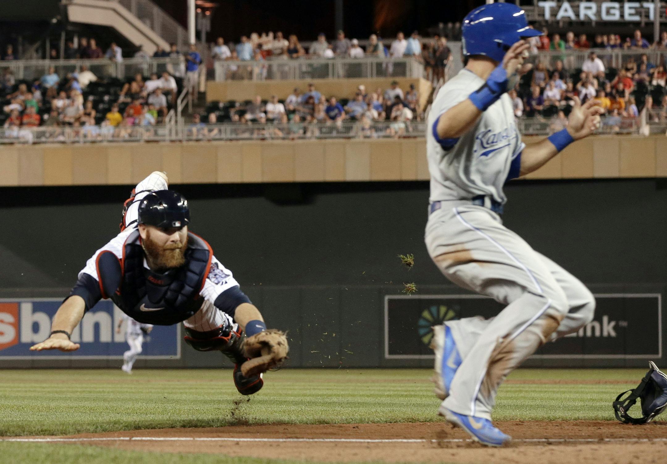 Minnesota Twins catcher Ryan Doumit, left, makes a futile dive as Kansas City Royals' David Lough runs by to score on a bunt single by Jarrod Dyson in the eighth inning of a baseball game, Tuesday, Aug. 27, 2013 in Minneapolis. The Royals won 6-1. (AP Photo/Jim Mone)