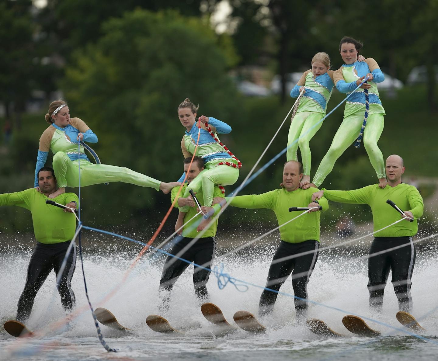 United States: c. 1956 Three members of the Min-Aqua Bats Waterski Club  take the jump simultaneously as part of the water ski show. - SuperStock