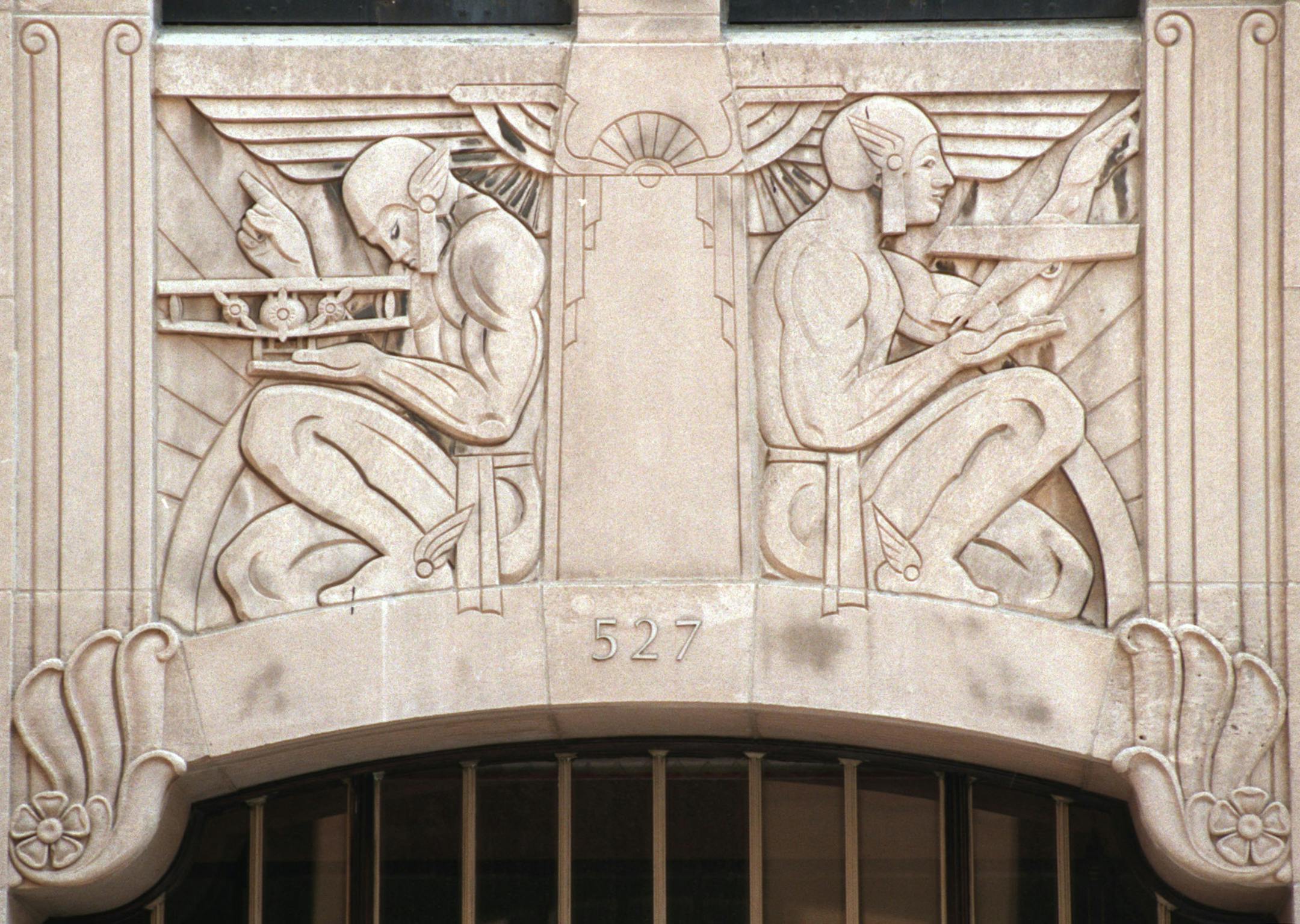 Two Mercury-like figures, each with a plane, ornament one of the five entries to the Rand Tower at 527 Marquette Avenue. The Art Deco building was built in 1928, designed by Holabird and Root.
