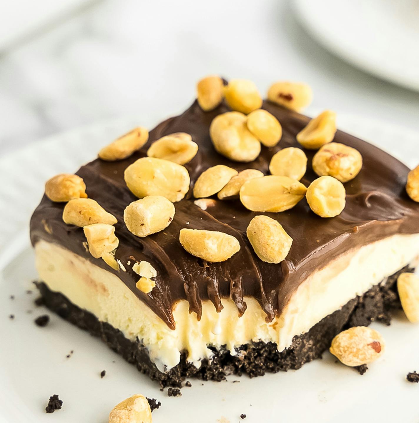 A slice of Buster Bar Dessert, with chocolate, ice cream and peanuts.