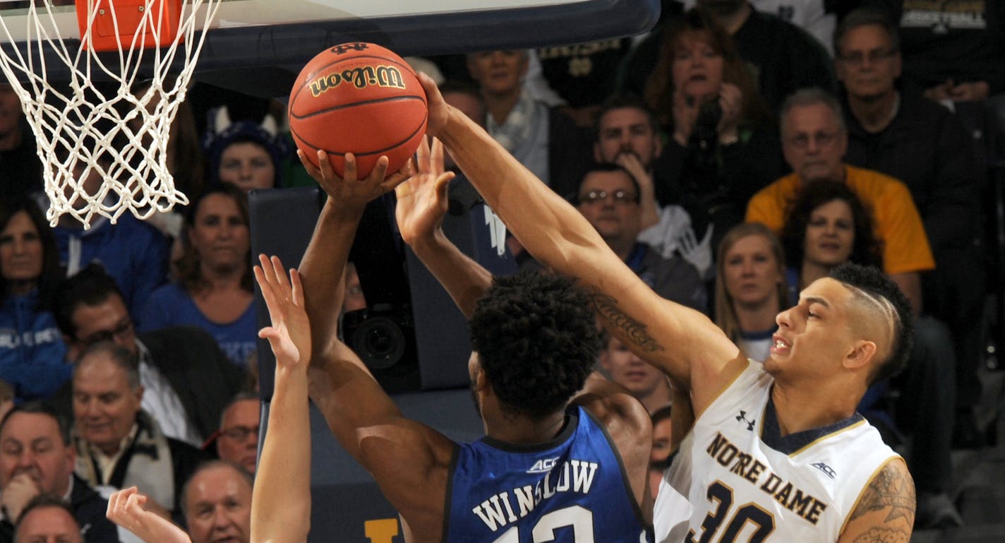 Duke guard Justice Winslow has his shot blocked by Notre Dame guard Steve Vasturia, left, and Zach Auguste in the first half of an NCAA college basketball game Wednesday, Jan. 28, 2015, in South Bend, Ind. (AP Photo/Joe Raymond)