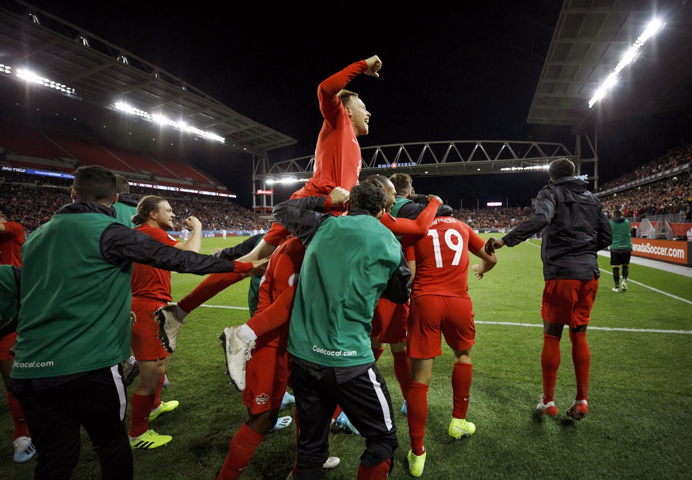 Canada midfielder Scott Arfield, top, and teammates celebrate a goal by forward Lucas Cavallini (19) in a CONCACAF Nations League soccer match against the United States on Oct. 15 in Toronto.