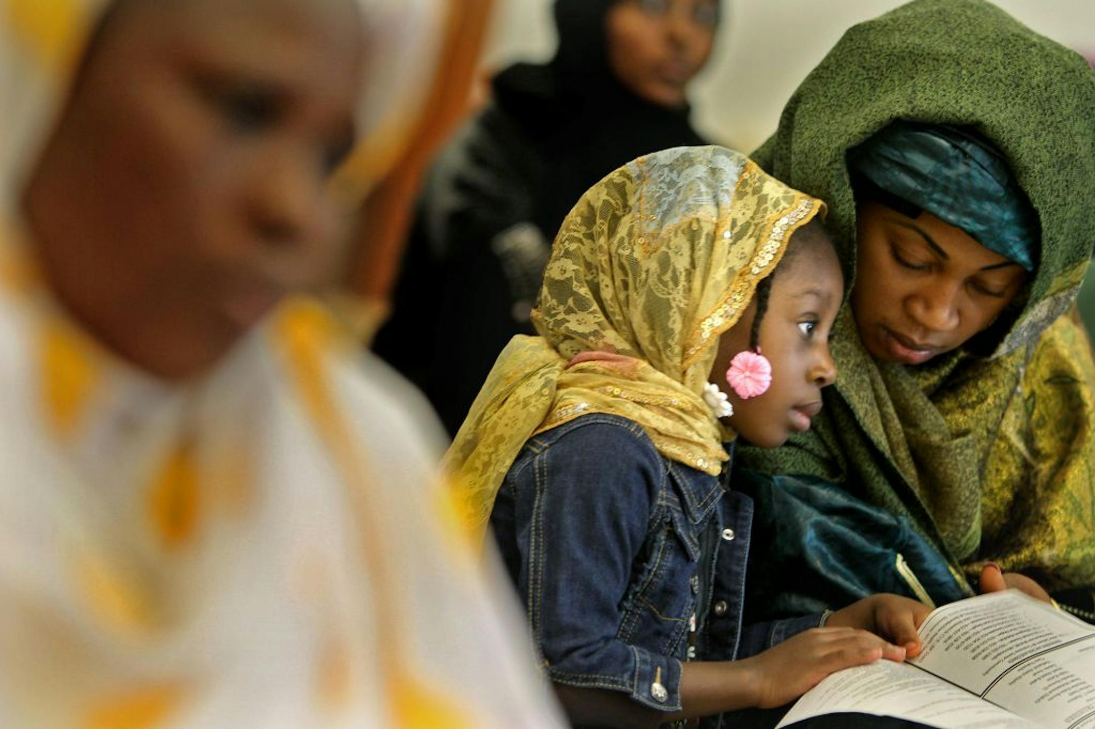 Mafanta Sonnoe and her 4-year-old Aminata Sonnoe read along a statement on violence in Libya and Egypt with Imam Makram El-Amin at the Masjid An-Nur Mosque of the Ligh as worshippers gathered to observe Friday prayers at the mosque, September 14, 2012 in Minneapolis, MN. (ELIZABETH FLORES/STAR TRIBUNE) ELIZABETH FLORES � eflores@startribune.com