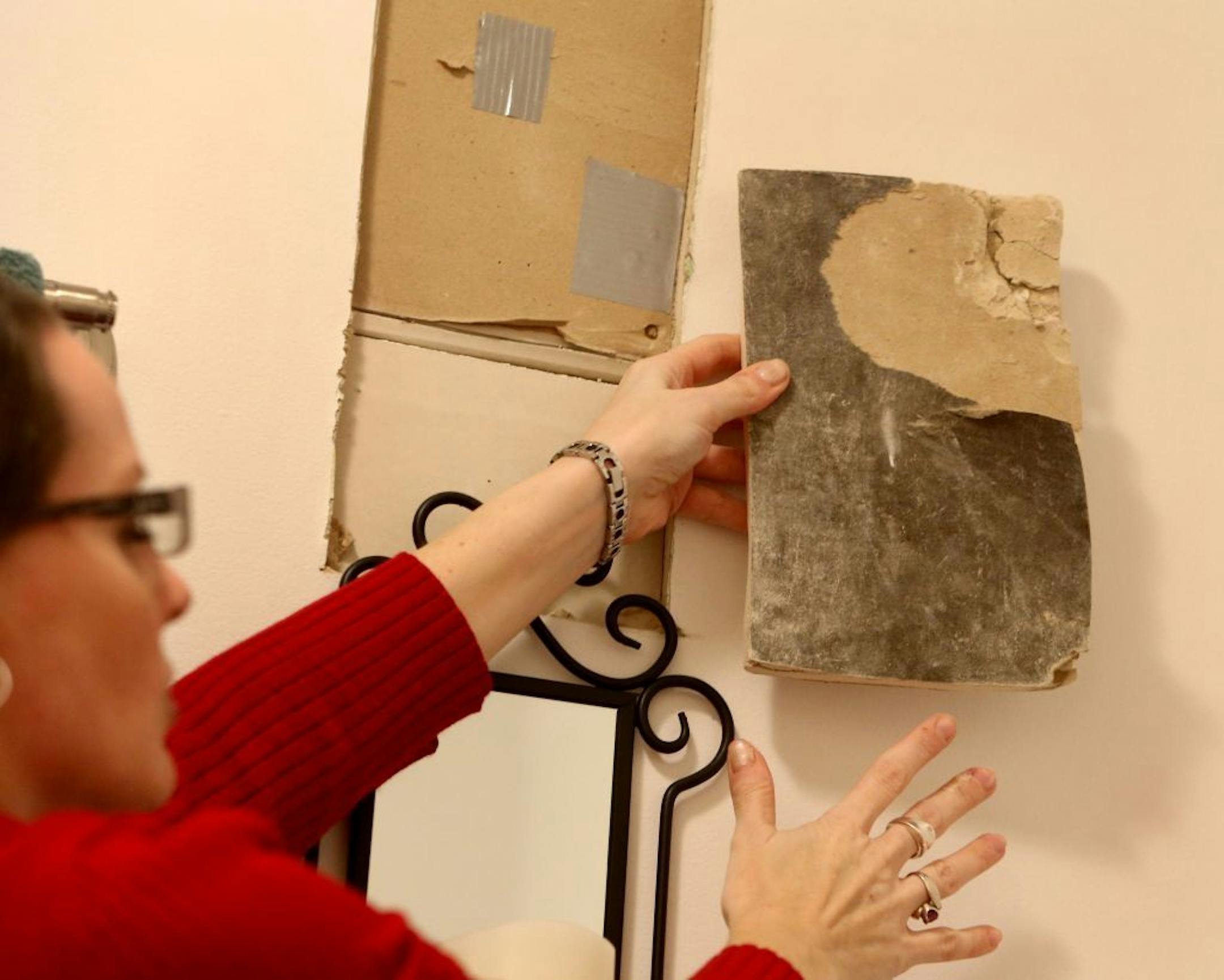 After living for two years with mold, water, indoor snow and flying squirrels, Tina Nelson doesn't know where else to turn for help with her Edina condo. Here, Nelson shows a piece of wet and moldy sheet rock that had to be cut out from the bathroom wall, caused by leaking in the roof and seen Friday, Dec. 11, 2015, in Edina, MN.