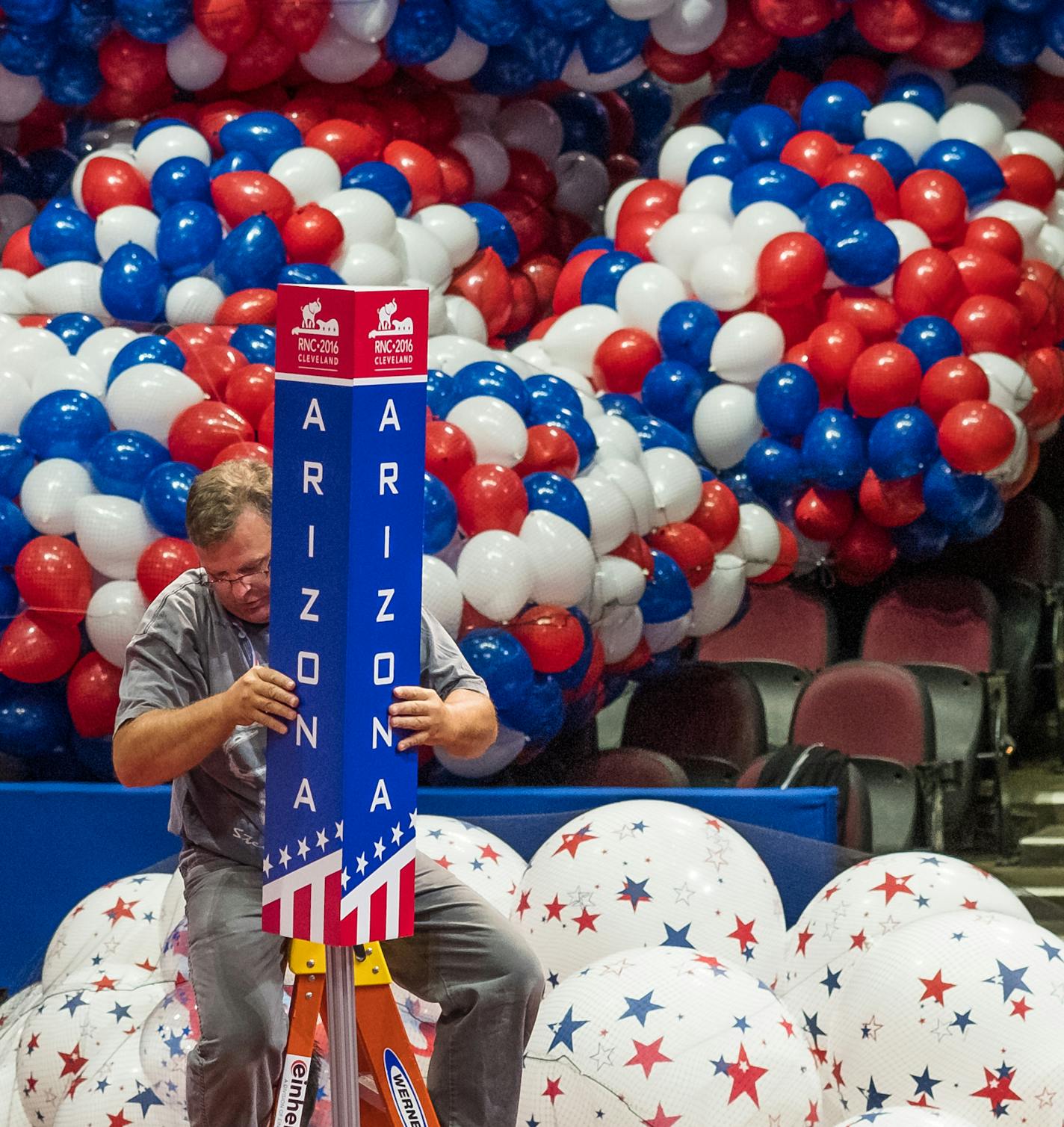 A member of the construction crew hangs the Arizona delegation sign on the convention floor, Friday, July 15, 2016, in Cleveland, as preparations continue for the opening of the Republican National Convention Monday. (AP Photo/J. David Ake)