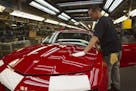 FILE - In this June 10, 2011, file photo, a worker checks the paint on a Camaro at the GM factory in Oshawa, Ontario. General Motors is closing a Cana