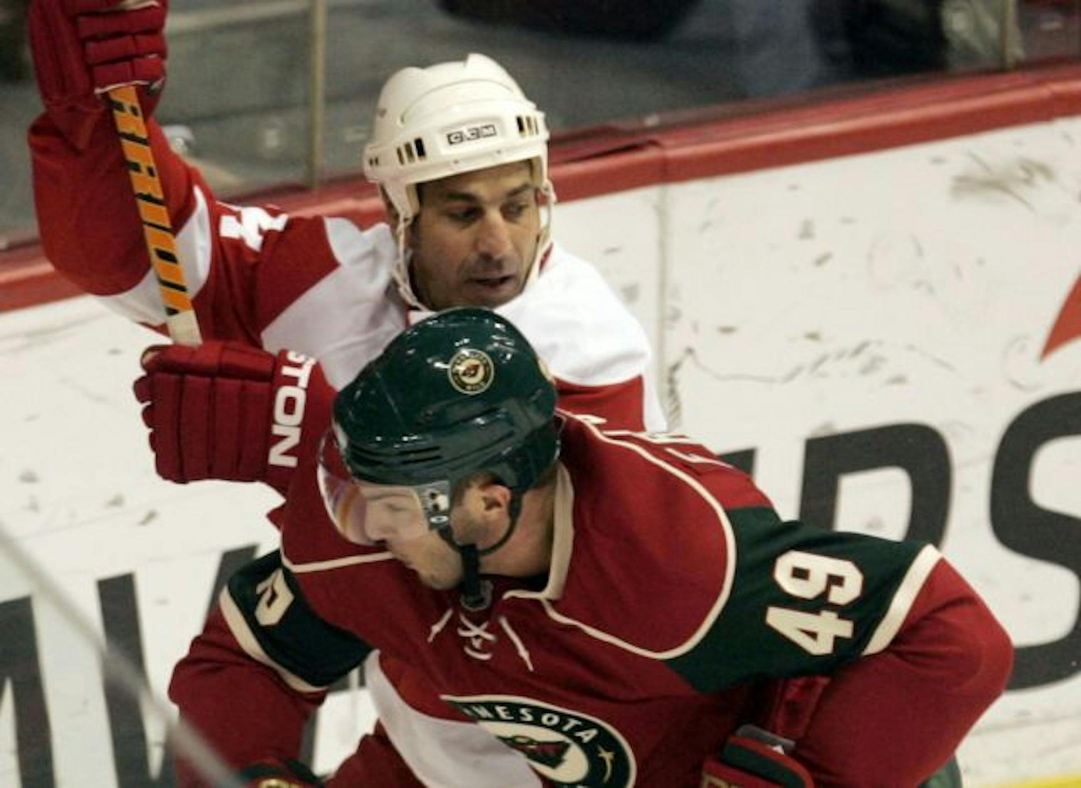 The Minnesota Wild's Dan Fritsche (49) and the Detroit Red Wings Chris Chelios (24) mix it up during first period action at the Xcel Energy Center.