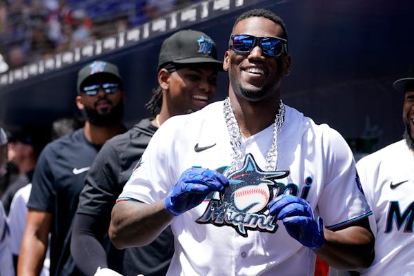 Miami's Jorge Soler holds up a chain necklace in the dugout after hitting a solo home run during the first inning against the Twins on Wednesday