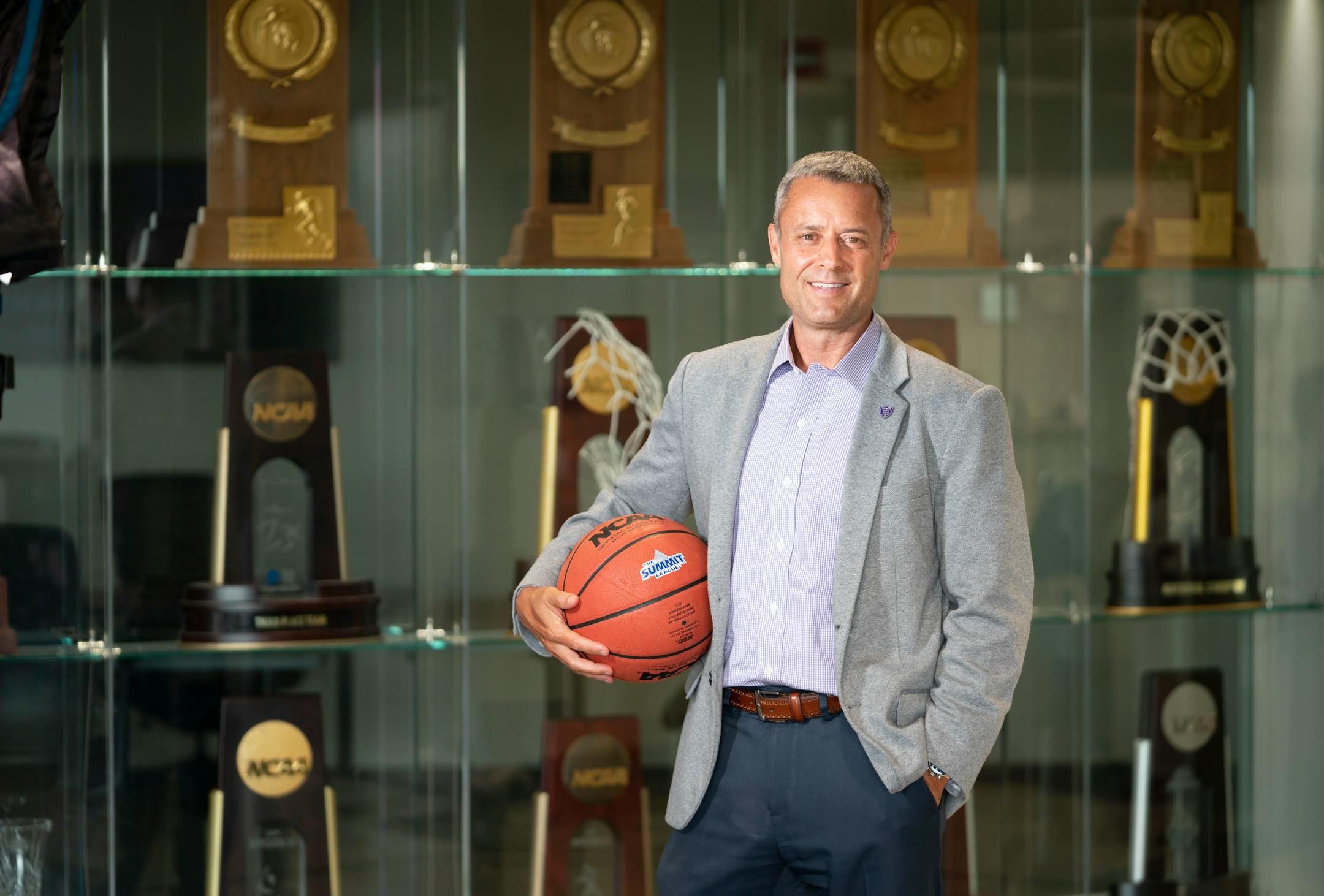 Athletic Director Phil Esten stood for a photo in front of the trophy case at the University of St. Thomas