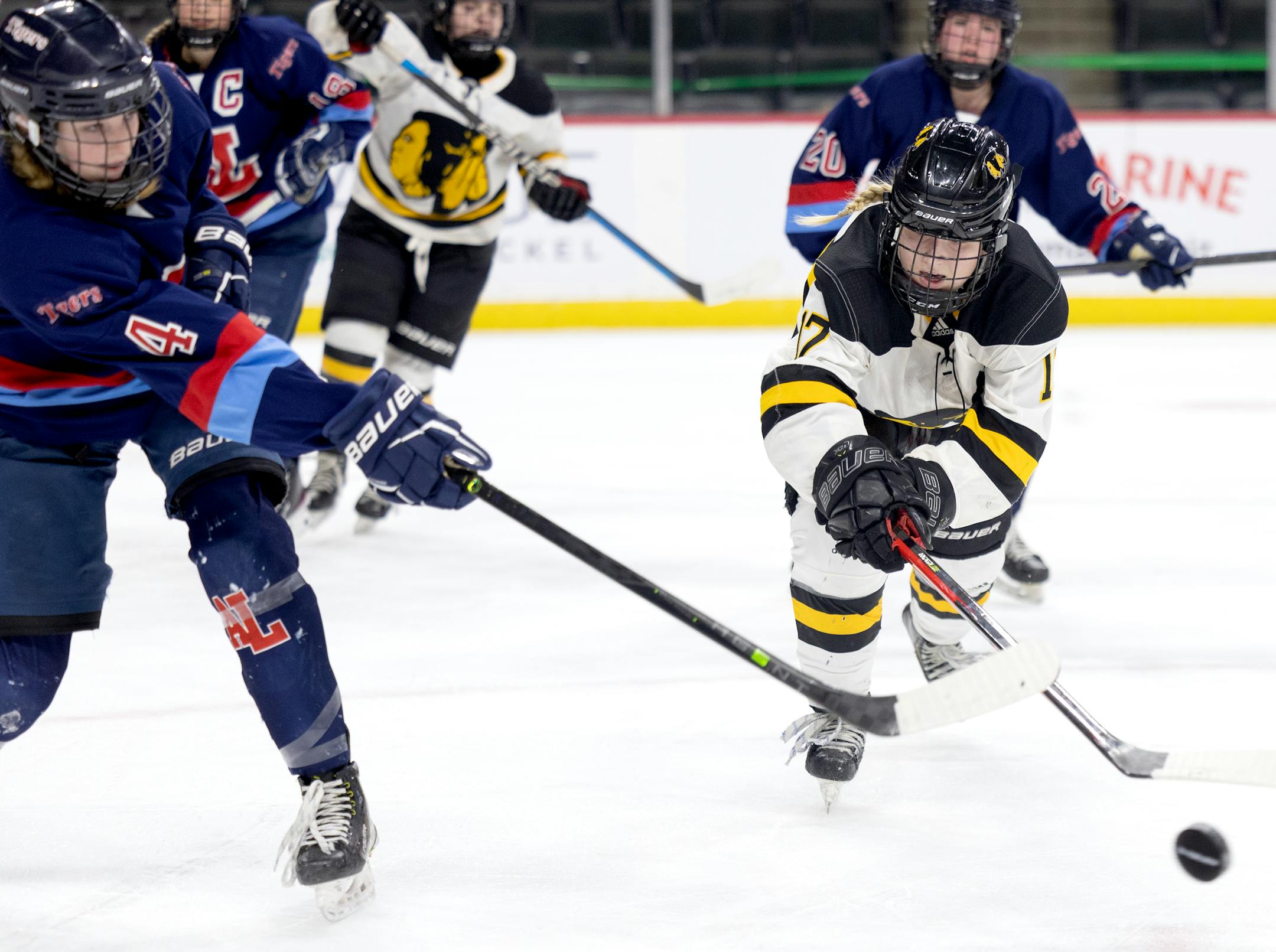 Sydney Kolker (4) of Albert Lea and Abbey Reule (17) of Warroad fight for the puck in the first period during the Class 1A quarterfinals Wednesday, February 22, 2022, at Xcel Energy Center in St. Paul, Minn,