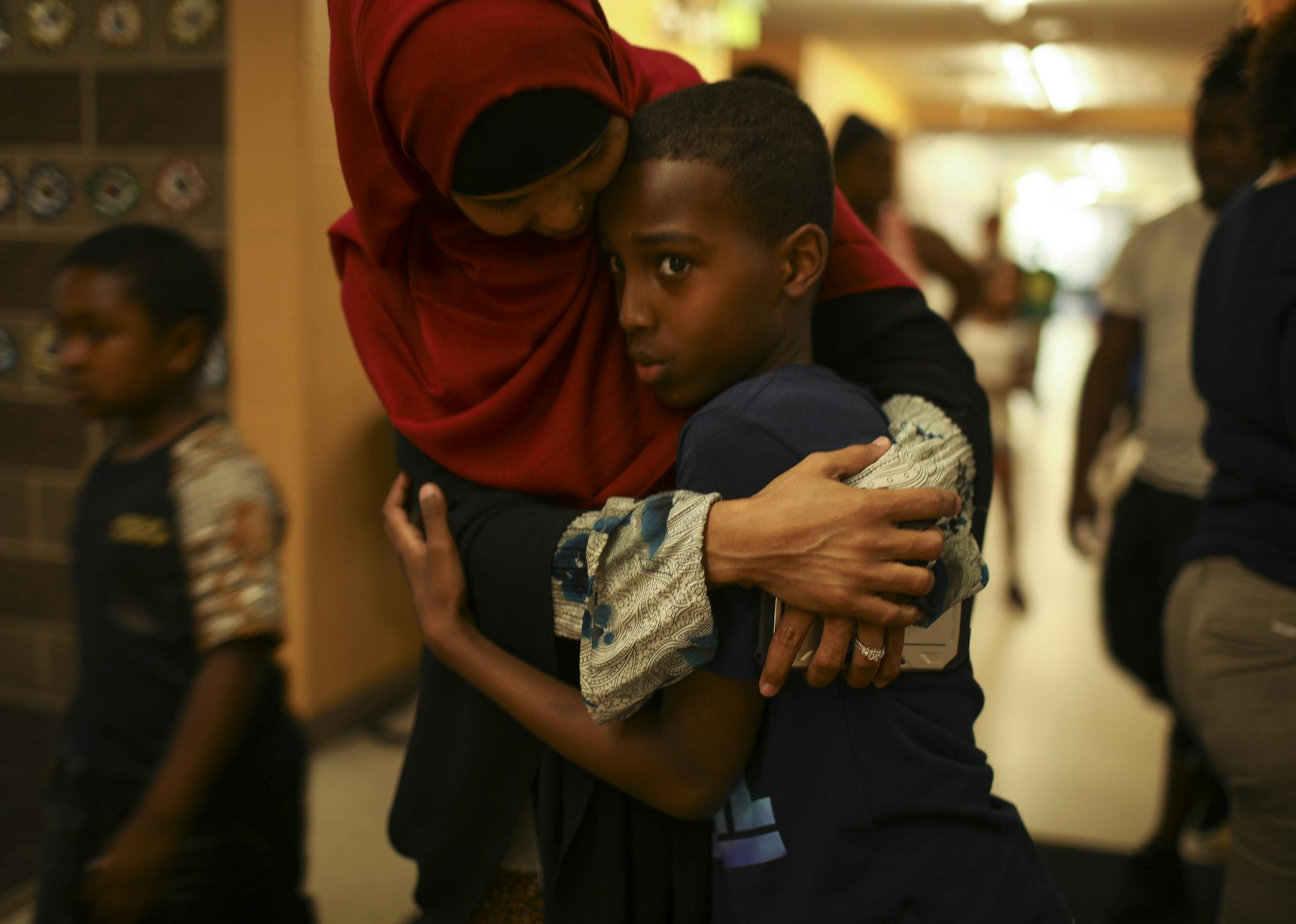 Shukri Abdul, hugged her son, Yahya, 12, when she picked him up Thursday from the neighborhood rec center. Abdul, a single mom of five in St. Paul, is flying to Malaysia on Monday to be with her fiance for his visa interview.