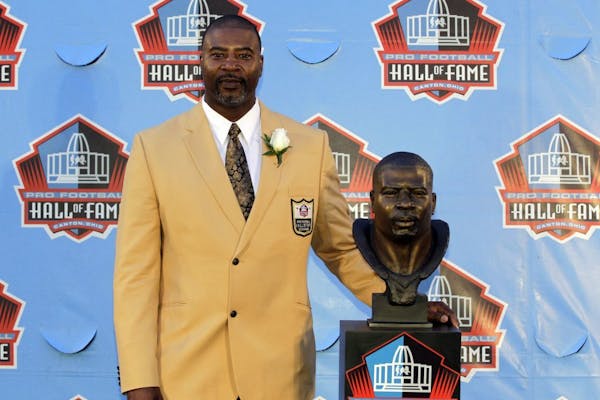 Former NFL player Chris Doleman poses with a bust of himself during an induction ceremony at the Pro Football Hall of Fame, Saturday, Aug. 4, 2012, in