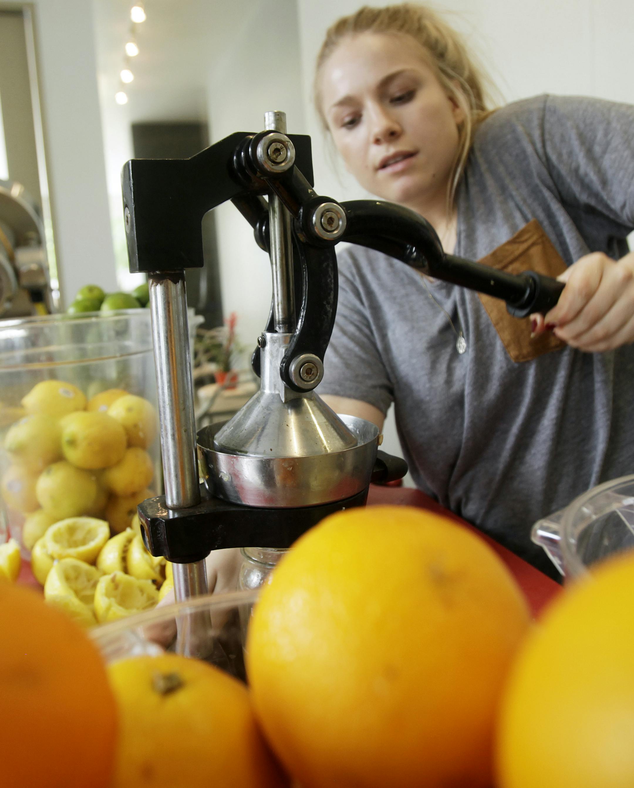 Ingrid Miller (right) hand squeezes lemons as she prepares juice to be bottled as Haley Fleming (left) prepares other ingredients to be chopped at Truce in Minneapolis, MN May 31, 2013. ] JOELKOYAMA‚Ä¢joel koyama@startribune.com