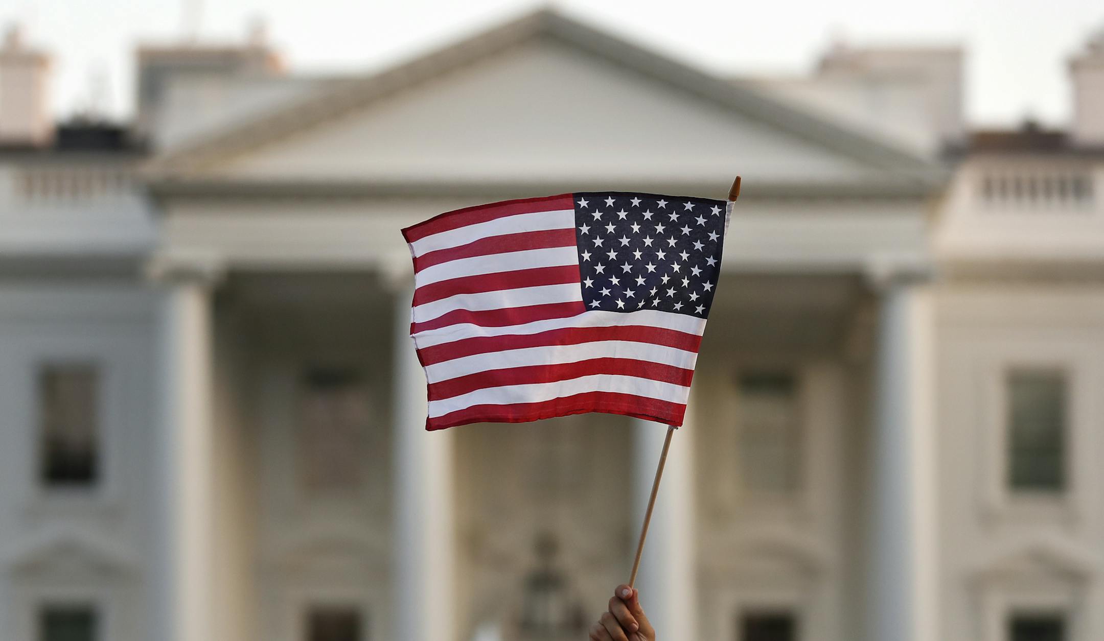 FILE - In this Sept. 2017 file photo, a flag is waved outside the White House, in Washington. The Trump administration announced Friday that it was curbing legal immigration from six additional countries that officials said did not meet security screening standards, as part of an election-year push to further restrict immigration. Officials said immigrants from Kyrgyzstan, Myanmar, Eritrea, Nigeria, Sudan and Tanzania will face new restrictions in obtaining certain visas to come to the United St