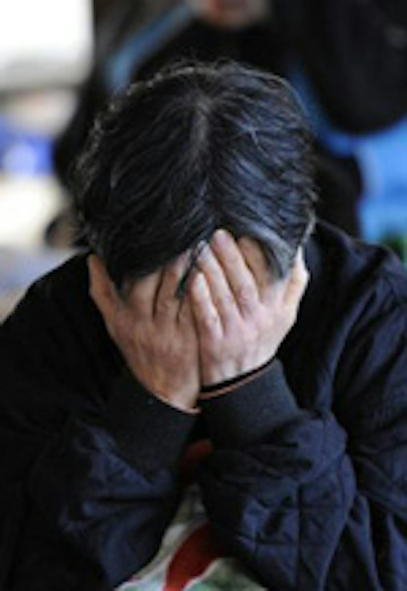 A woman evacuee covers her face at a shelter in Higashimatsushima.