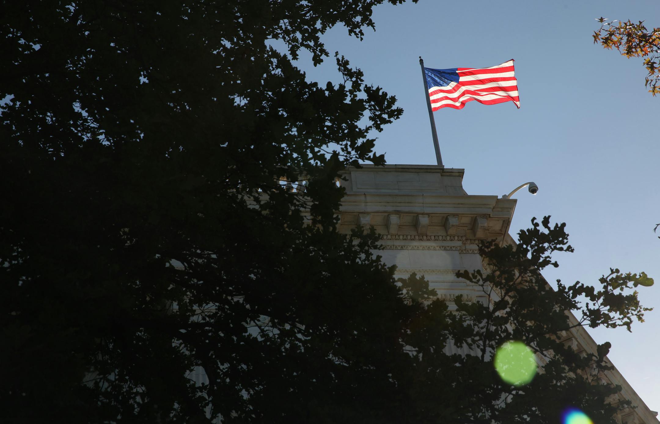 A flag blows in a breeze on the Russell Senate Office building on the fifteenth day of the US government shutdown in Washington D.C., U.S., on Tuesday, Oct. 15, 2013. The fiscal showdown in Washington entered its final stages as the House and Senate prepared competing plans that would end the 15-day-old government shutdown and prevent the U.S. from missing promised payments. Photographer: Julia Schmalz/Bloomberg