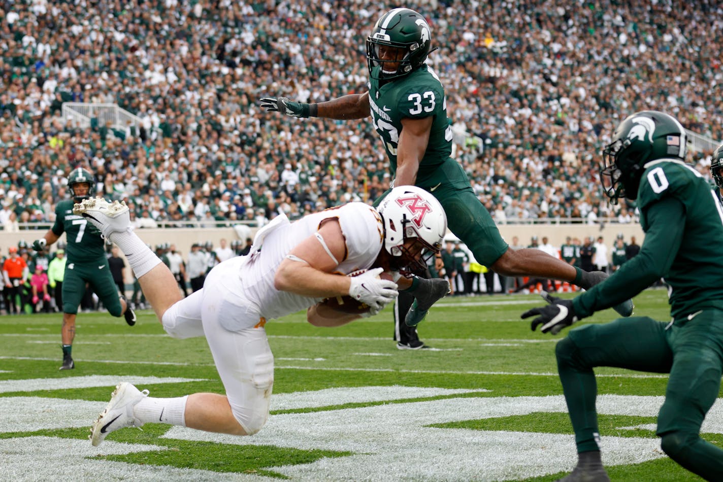 Gophers tight end Nick Kallerup catches a touchdown against Michigan State's Kendell Brooks (33) and Charles Brantley, right, during the second half Saturday