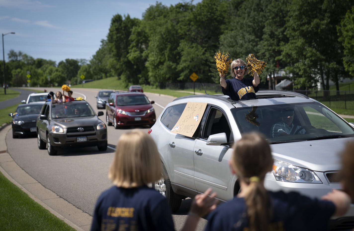 Glendale Elementary School teacher Karla Schutz waved to students who lined streets in their neighborhoods as staff from the school drove a parade of cars down the streets of Savage, Minn. on the last day of school on Thursday, June 4, 2020.