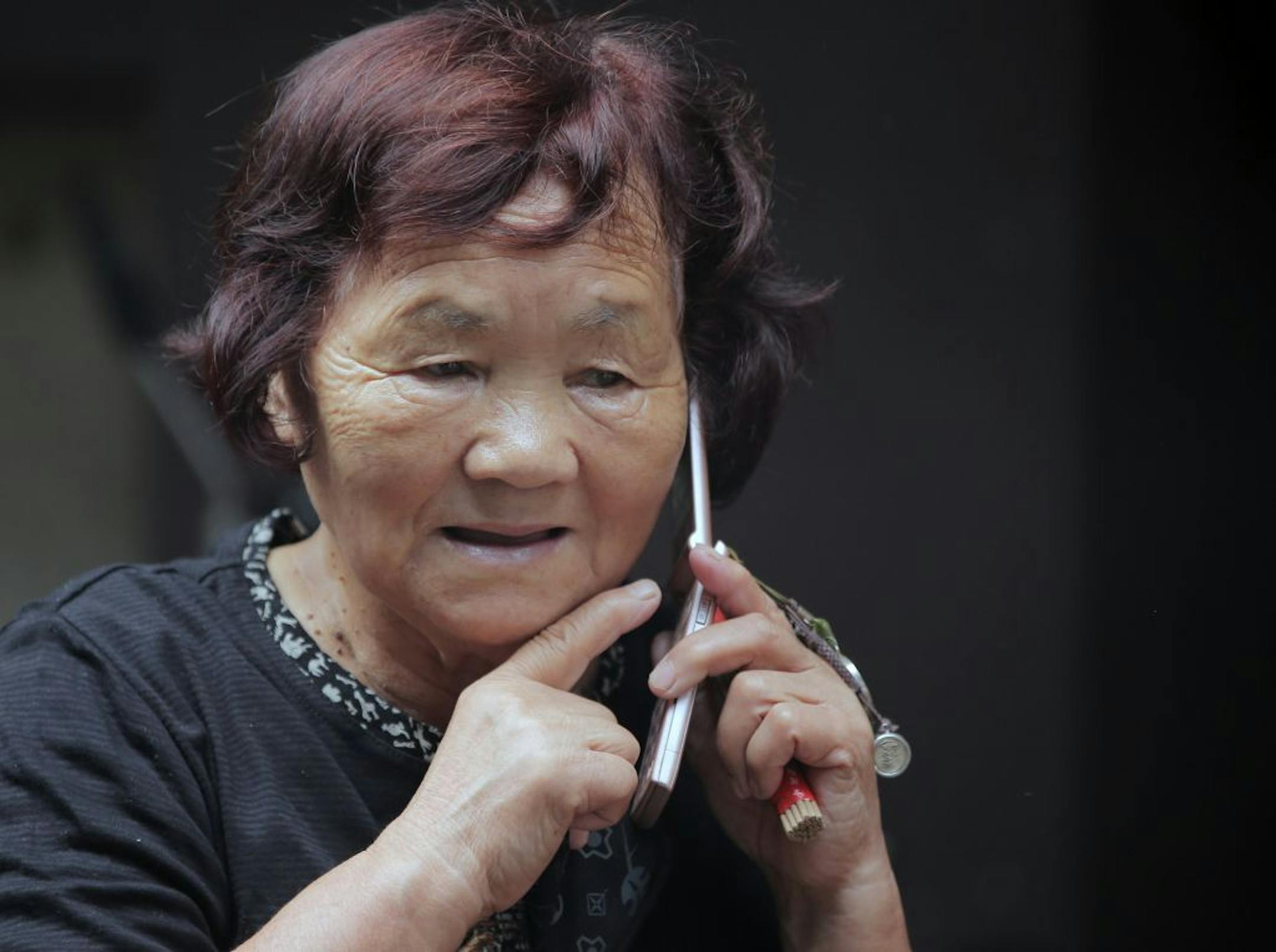 In this Saturday, Sept. 29, 2012 photo, an elderly woman speaks on her mobile phone at a shrine in Tokyo. The U.N. Population Fund has urged governments to build safety nets to ensure that older people have income security and access to essential health and social services as the world's elderly population grows. The U.N. agency said discrimination toward and poverty among the aged are still far too prevalent in many countries. It released its report Monday, Oct. 1, 2012 in Tokyo, capital of the